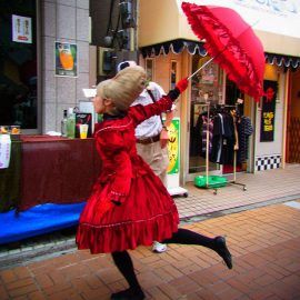 一際目立つ赤い衣装を着て路上パフォーマンスをするパントマイムアーティスト