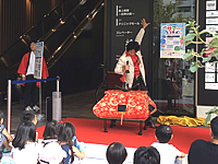 兵庫県尼崎市のファミリーが多く訪れる駅直結の商業施設の夏のイベントで人の入った箱に剣を突き刺すマジックを披露しているマジシャン 女性が中に入っている箱にマジシャンが剣を突き刺す様子