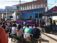 兵庫県姫路市にある自動車の販売・整備を行う会社のお客様感謝祭でこまつのパフォーマンスをご覧になる顧客様や近隣住民の方々の様子 立ち見も出るほど人気だった音楽芸人こまつのステージ