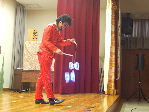 光るコマ(ディアボロ)でのジャグリングをする大道芸人